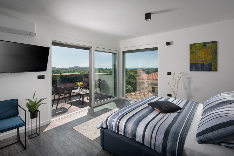 Chambre avec vue sur la verdure environnante et sur la mer.