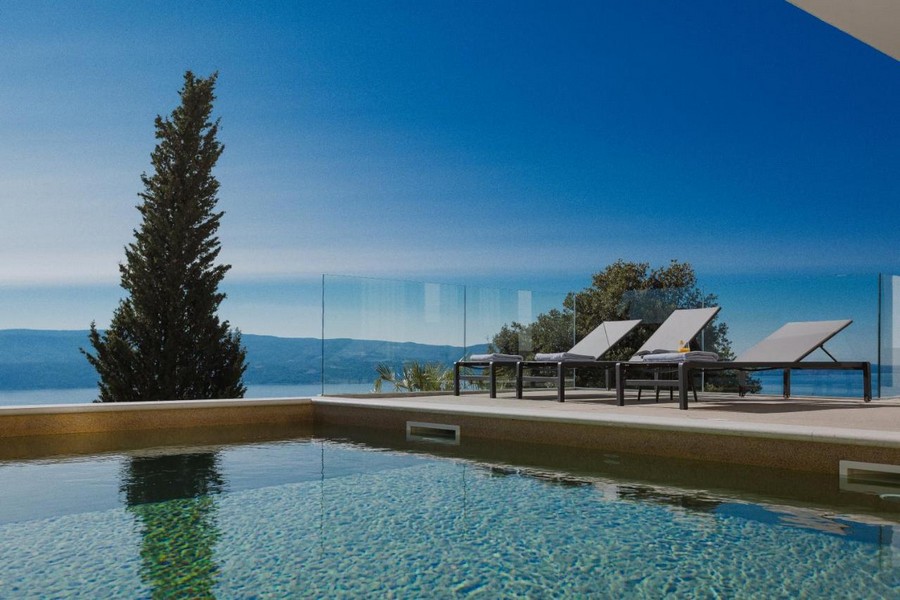 Piscine avec cyprès et transats devant la vaste vue sur la mer