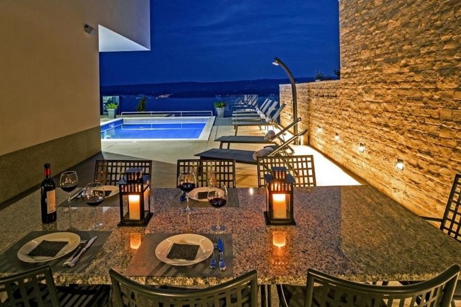 Table à manger et vue sur la piscine dans l'ambiance du soir.
