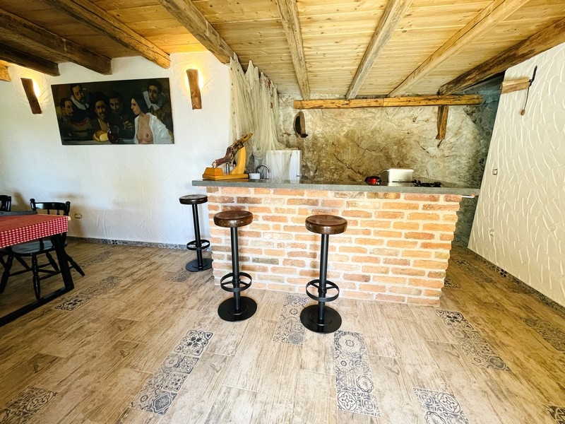 Taverne rustique avec comptoir en brique, plafond à poutres en bois et tabourets de bar
