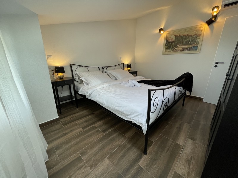 Chambre avec lit en fer forgé, parquet et appliques murales, avec vue latérale sur un tableau