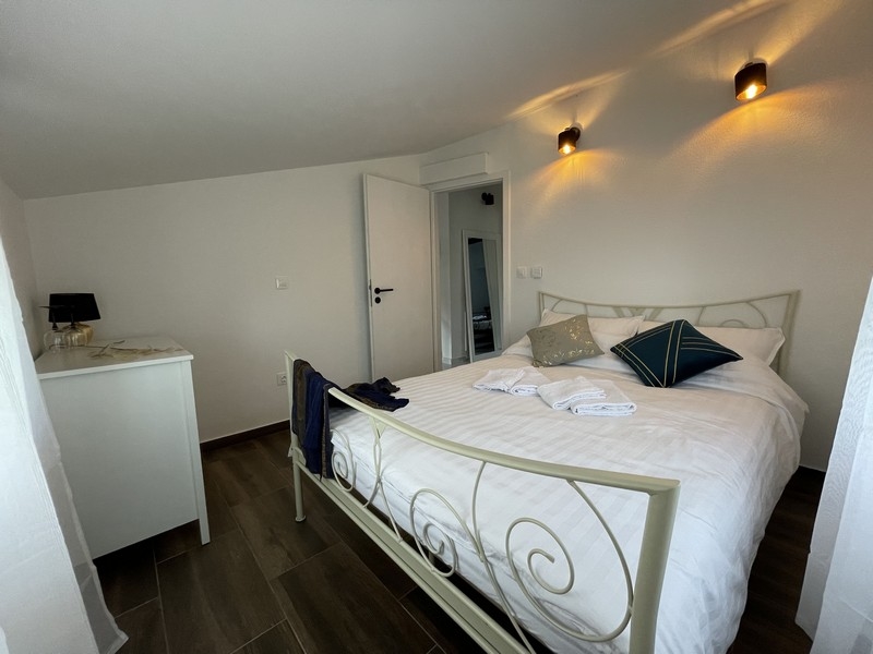 Chambre avec lit blanc en fer forgé, coussins décoratifs et ambiance moderne
