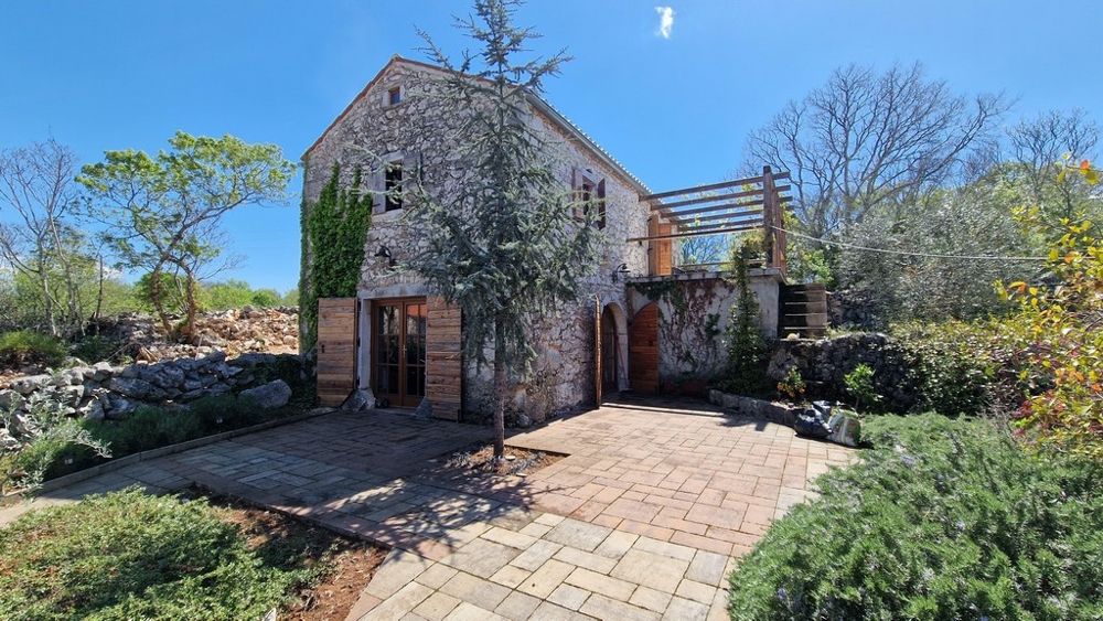 Ancienne maison en pierre avec lierre et portes en bois sur la cour pavée