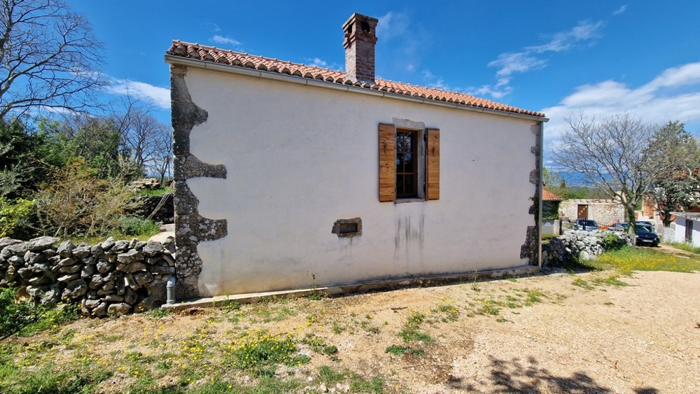 Vue d'une maison méditerranéenne traditionnelle avec détails en pierre et volets en bois.