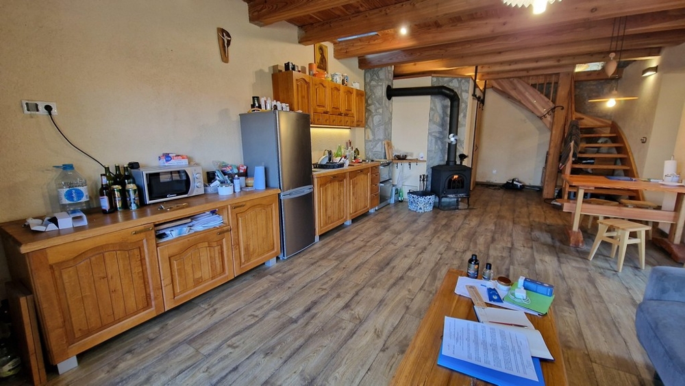 Cuisine avec placards en bois, réfrigérateur et table à manger de style rustique.