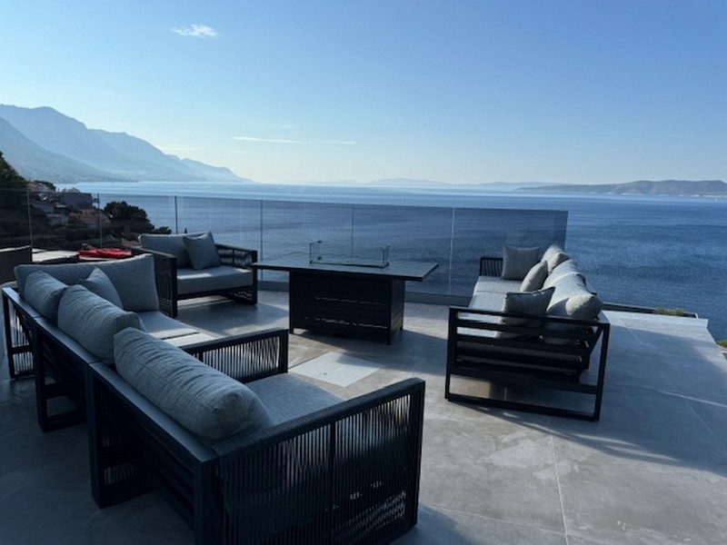 Coin salon avec table à feu sur la terrasse au-dessus de la baie