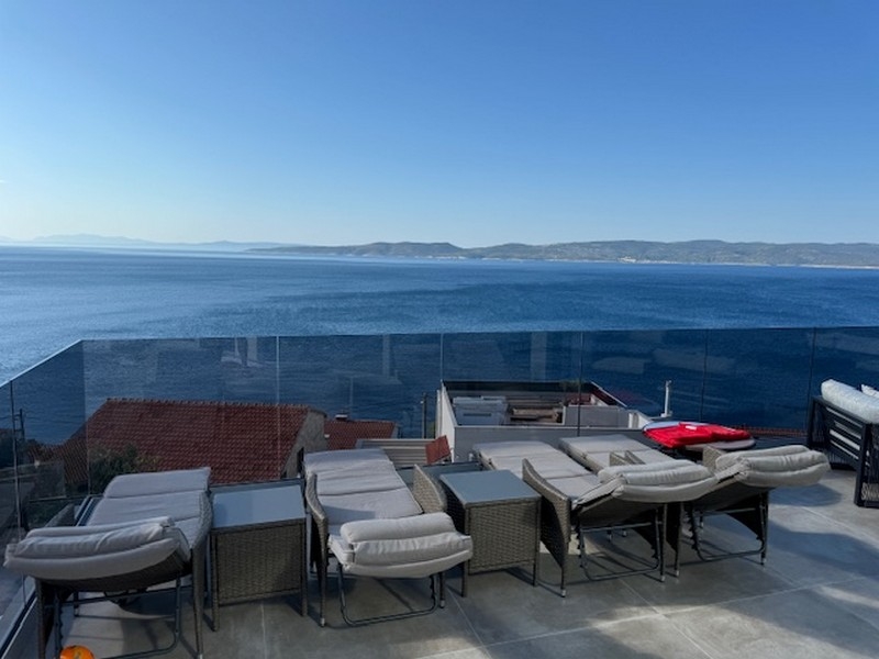 Toit-terrasse avec transats et garde-corps en verre au-dessus de la mer