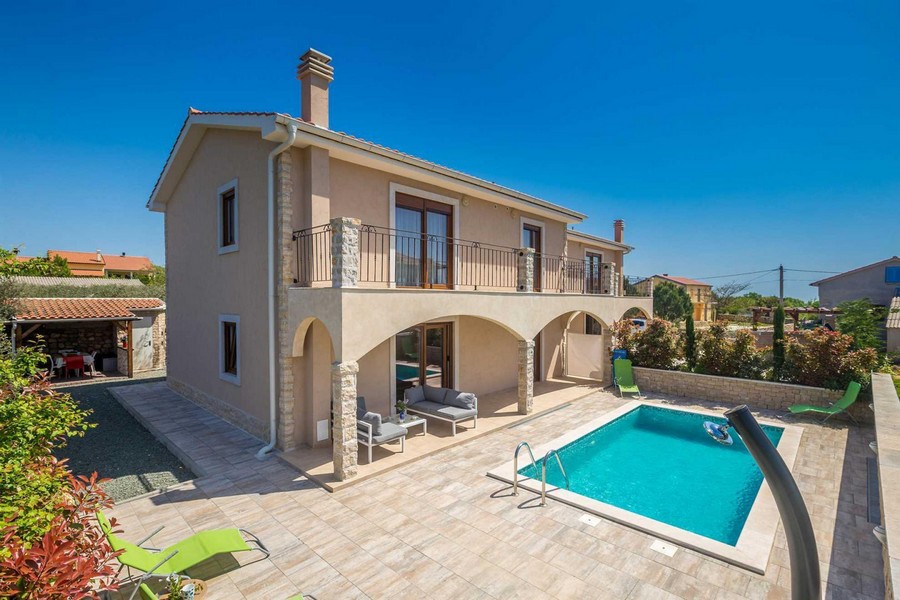 Maison avec arcades et balcon à côté de la piscine