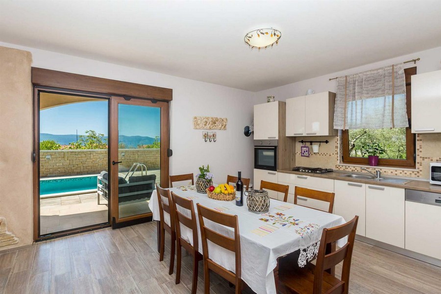 Coin repas, cuisine fonctionnelle et vue sur la piscine depuis la terrasse.