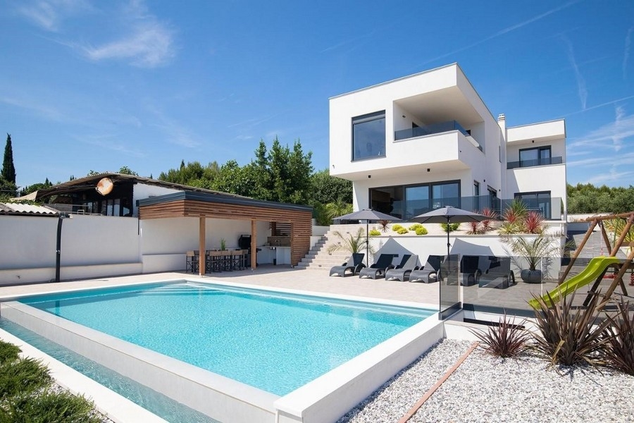 Villa blanche avec piscine et cuisine d'été sous un toit en bois