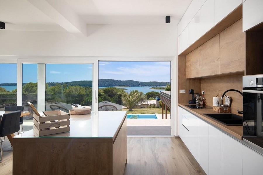 Cuisine moderne avec vue sur la piscine et la mer.