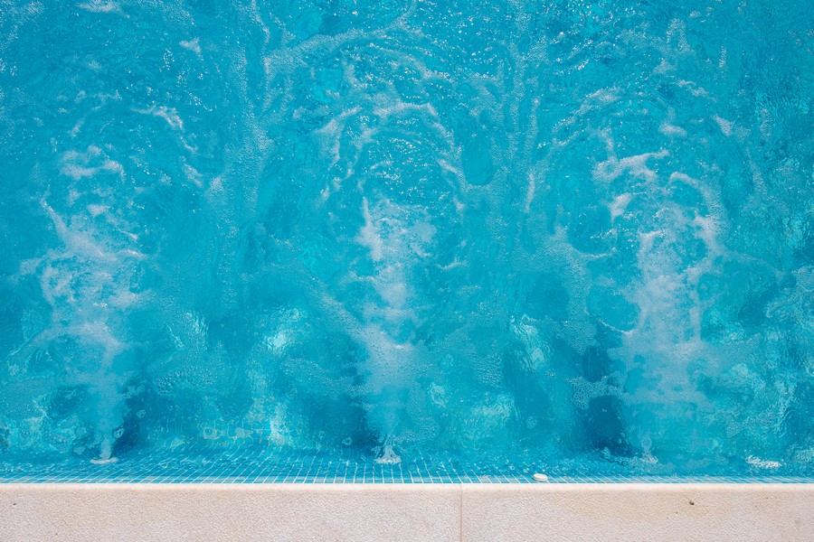 Gros plan de la piscine, eau qui bouillonne et carrelage d'un bleu éclatant.