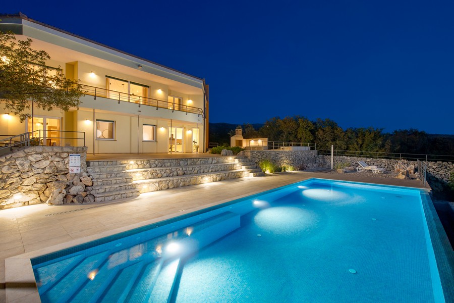 Villa H3417 de nuit, photographiée depuis la piscine.