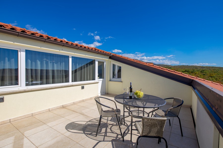 Vue extérieure de la terrasse avec coin salon et vue sur le paysage.