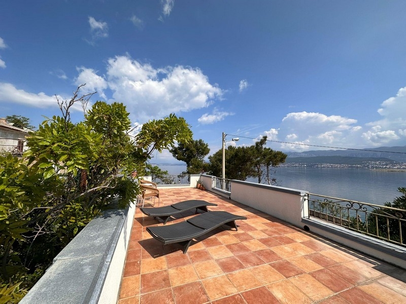 Terrasse avec transats et garde-corps en fer forgé au-dessus de la baie