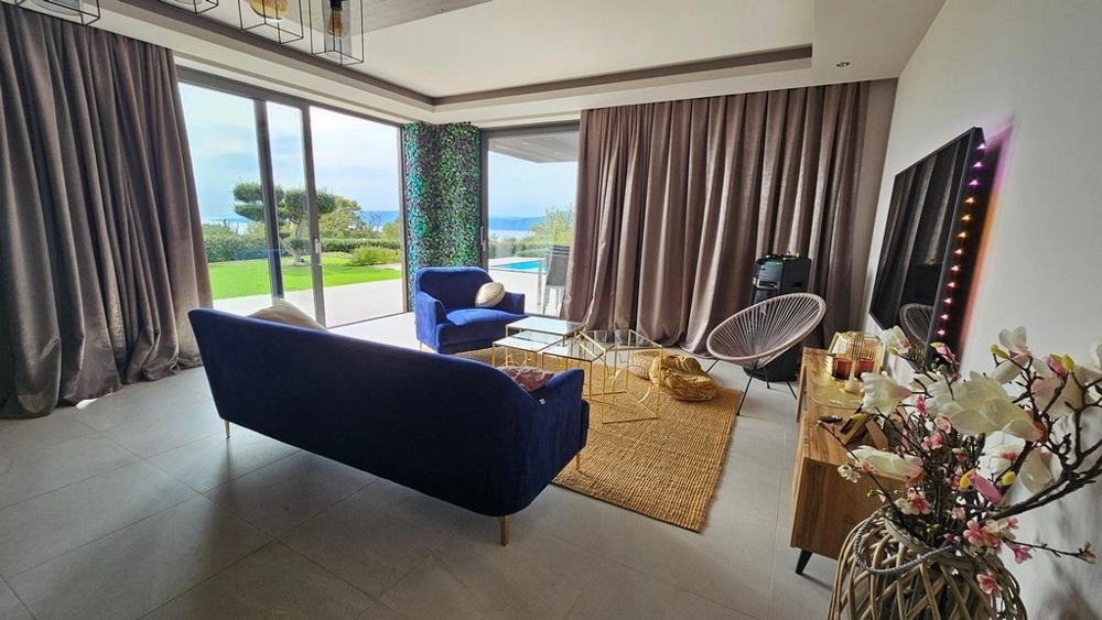 Salon avec vue sur la piscine et la mer.