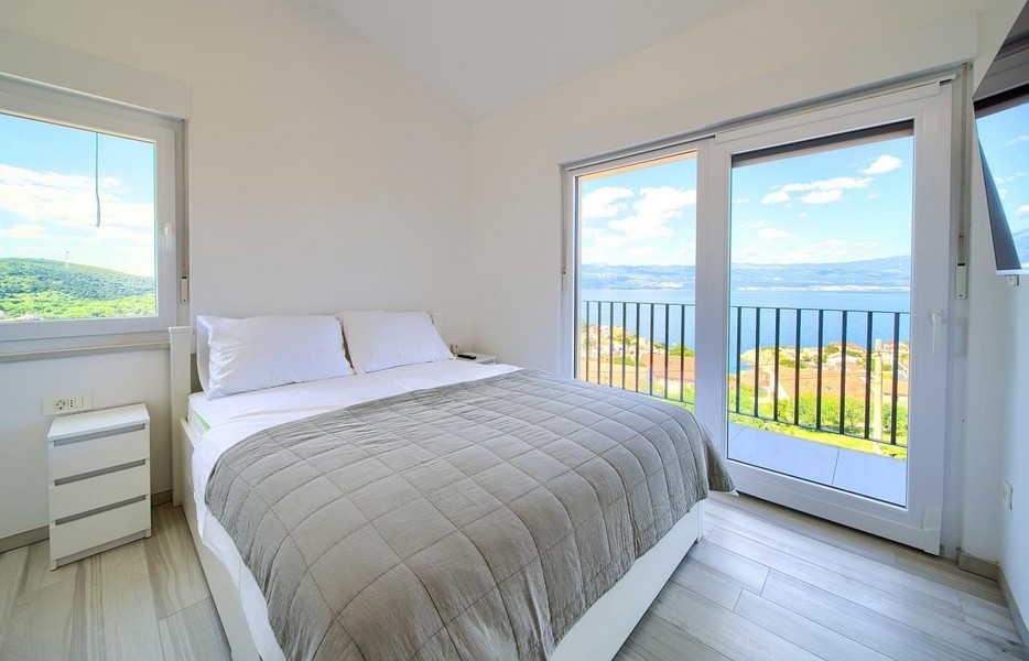 Chambre avec lit double et portes-fenêtres donnant sur le balcon, magnifique vue mer à l'arrière-plan