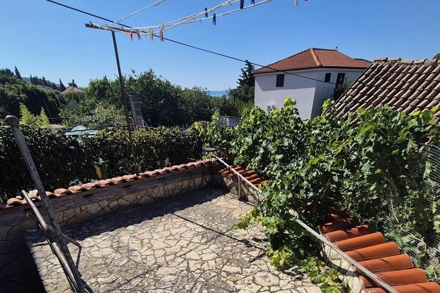 Terrasse en pierre avec feuillage de vigne et vue sur les toits jusqu'à la mer
