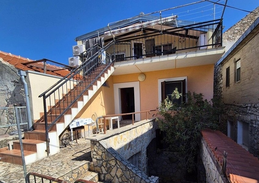 Vue arrière de la maison en pierre méditerranéenne avec escalier extérieur et terrasse.