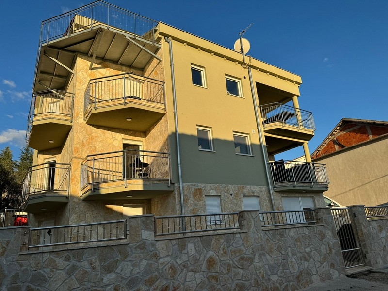 Maison jaune avec balcons et escalier extérieur à la lumière du soir