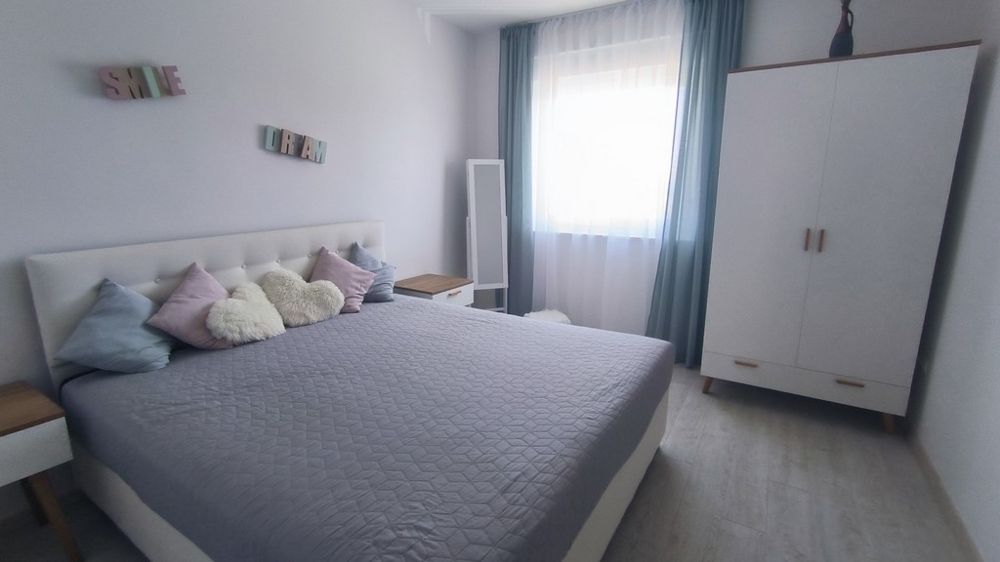 Chambre avec lit double, coussins décoratifs et armoire.