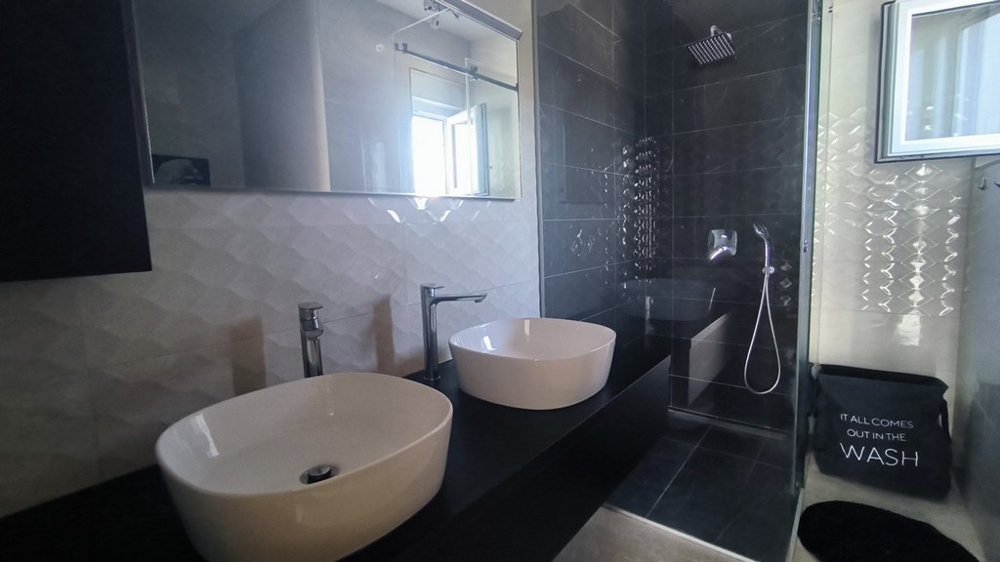Salle de bains moderne avec double vasque et douche à effet pluie.