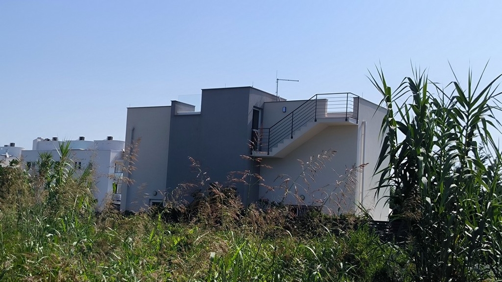 Vue arrière de la maison avec terrasse et escalier menant à l'étage.