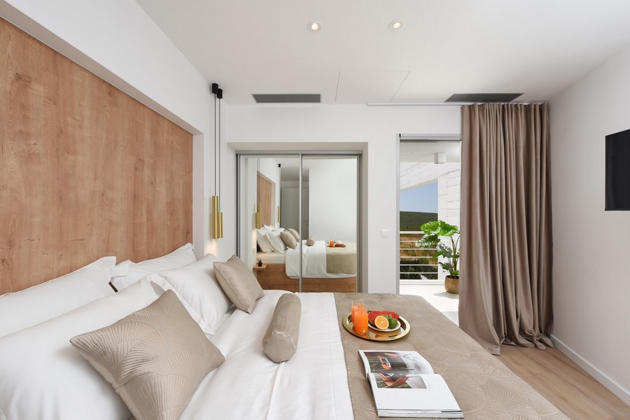 Chambre lumineuse avec accès au balcon, décoration dans des tons blancs et bois.