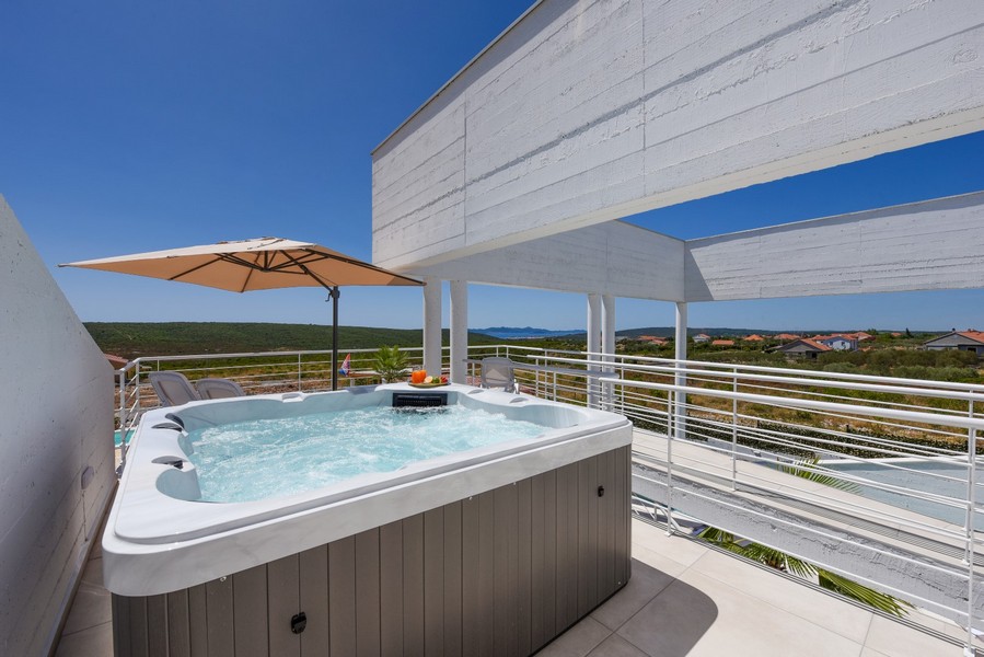 Jacuzzi extérieur sur la terrasse supérieure avec vue sur le paysage et la mer.