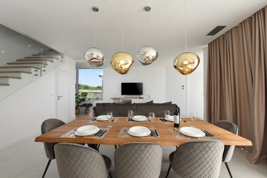 Coin repas moderne avec table en bois et luminaires design dans un concept de séjour ouvert.