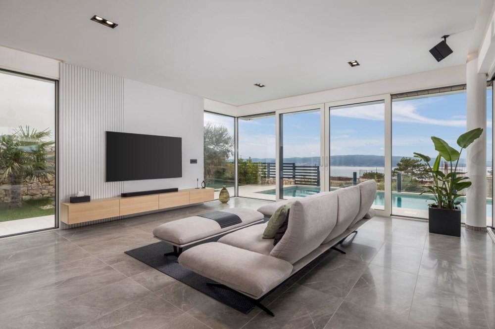 Séjour avec mur TV et vue sur la piscine et la mer