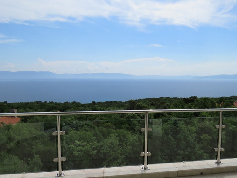 Garde-corps en verre avec vue sur la forêt, la mer et l'île
