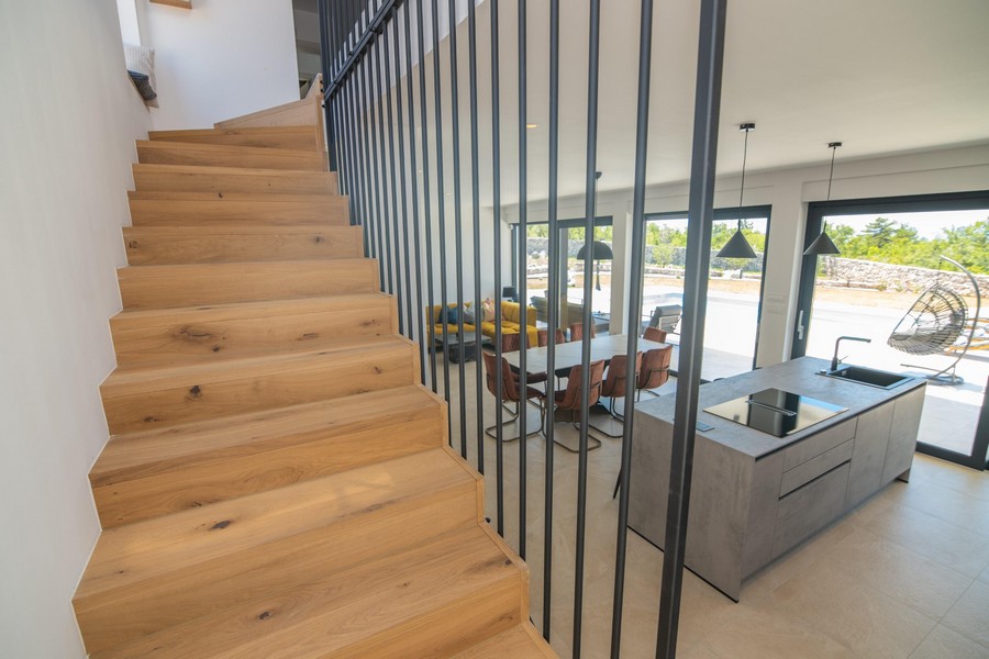 Escalier en bois avec rampe métallique, vue sur le séjour
