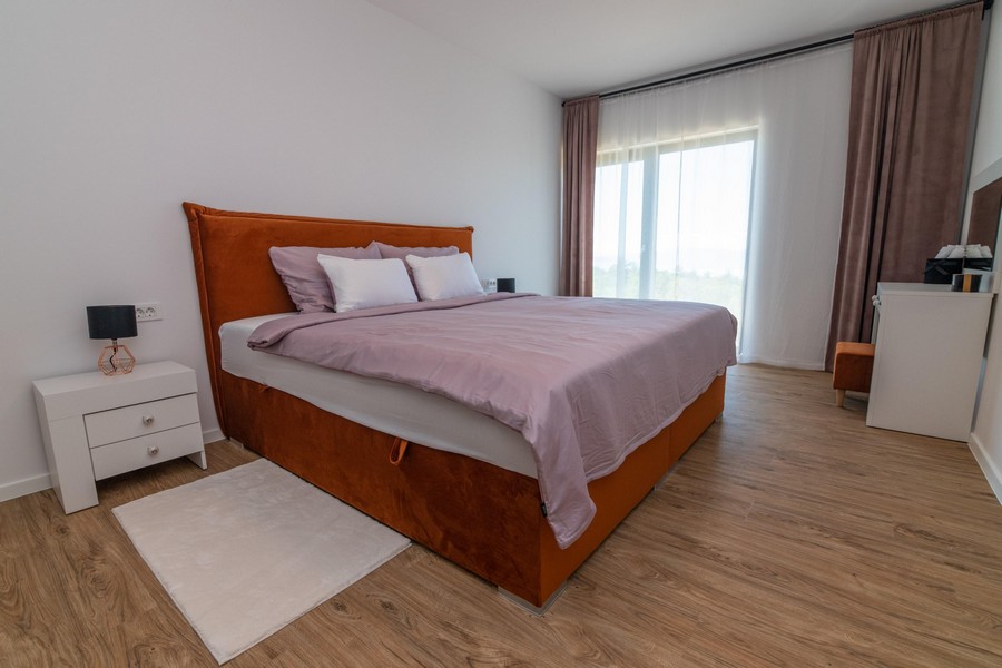 Chambre avec lit orange et grandes fenêtres