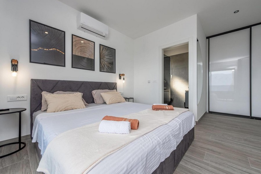 Chambre avec grand lit, tableaux muraux modernes et accès direct à la salle de bains.