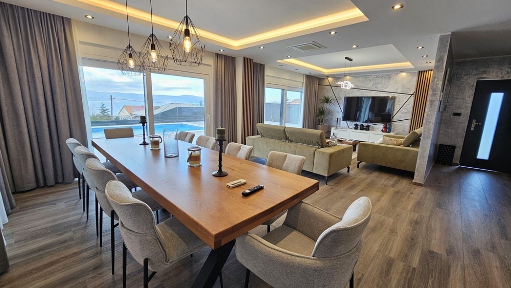 Salon moderne avec coin repas et vue sur la terrasse et la piscine