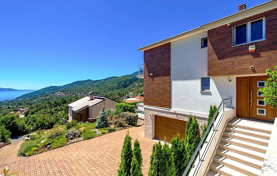 Vue extérieure de la villa avec cour pavée et garage