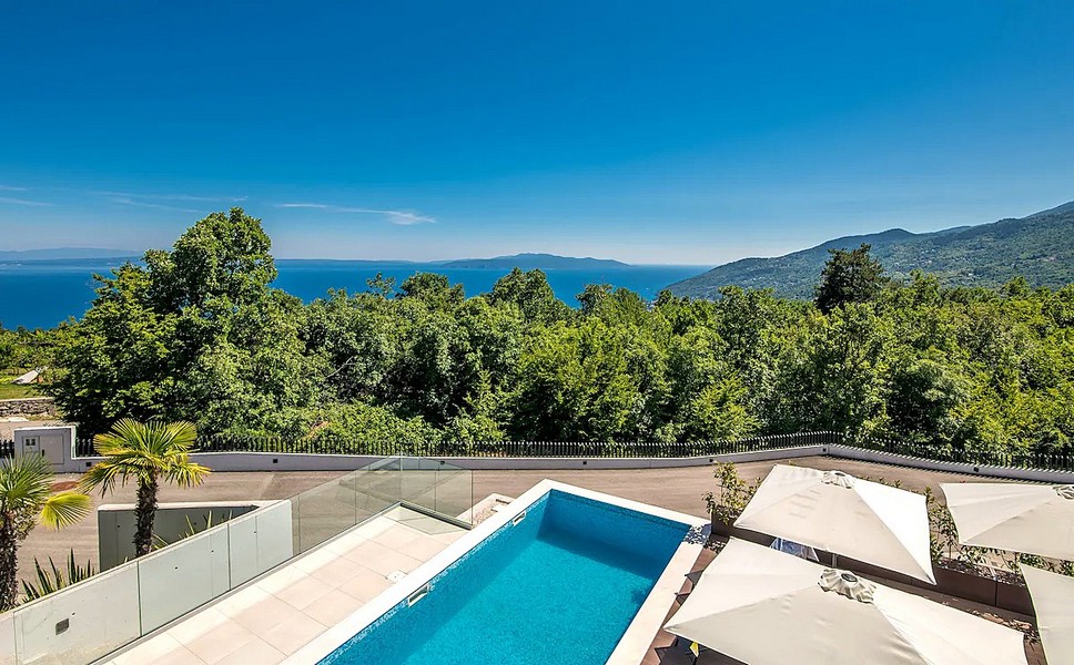 Piscine avec parasols et vue sur la forêt jusqu'à la mer