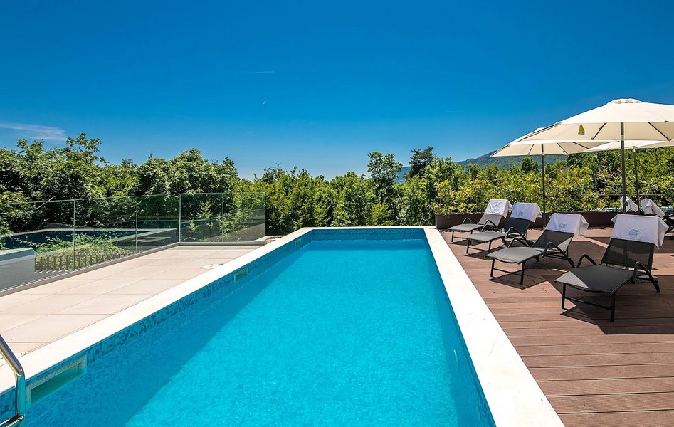 Piscine avec transats et parasol sur le deck en bois