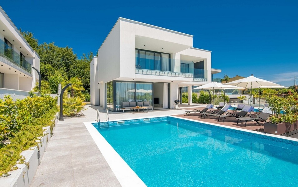 Villa blanche avec piscine et parasols dans un jardin de gravier