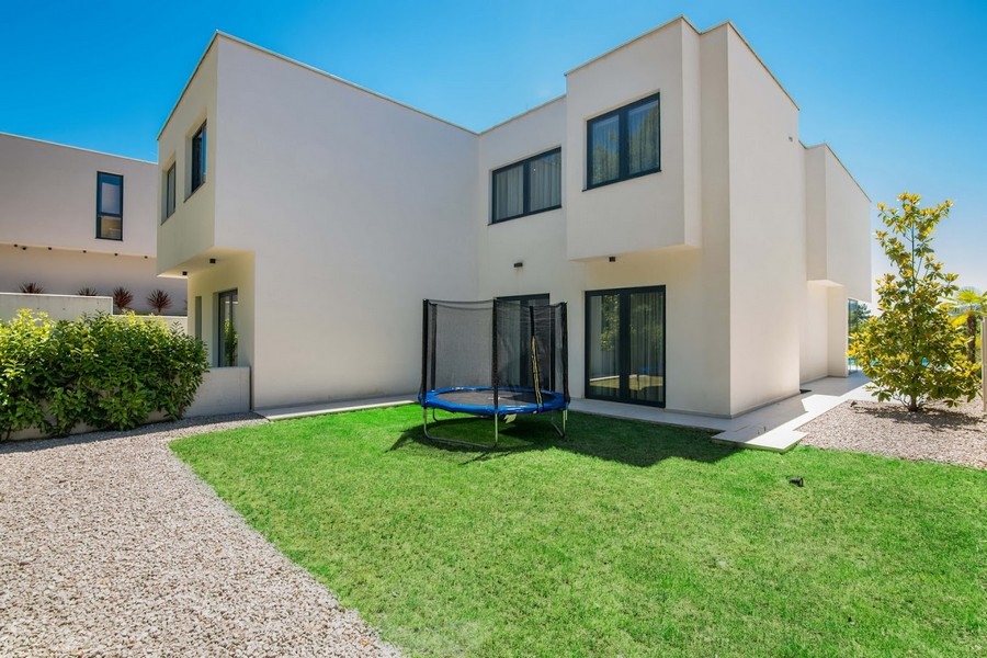 Jardin moderne avec maison jumelée et trampoline