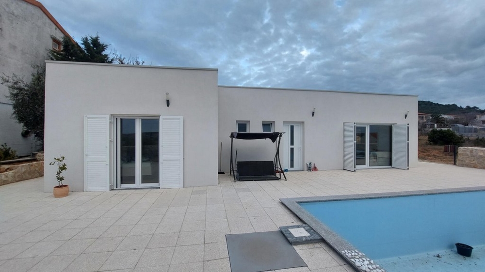 Maison à toit plat avec volets battants et balancelle près de la piscine