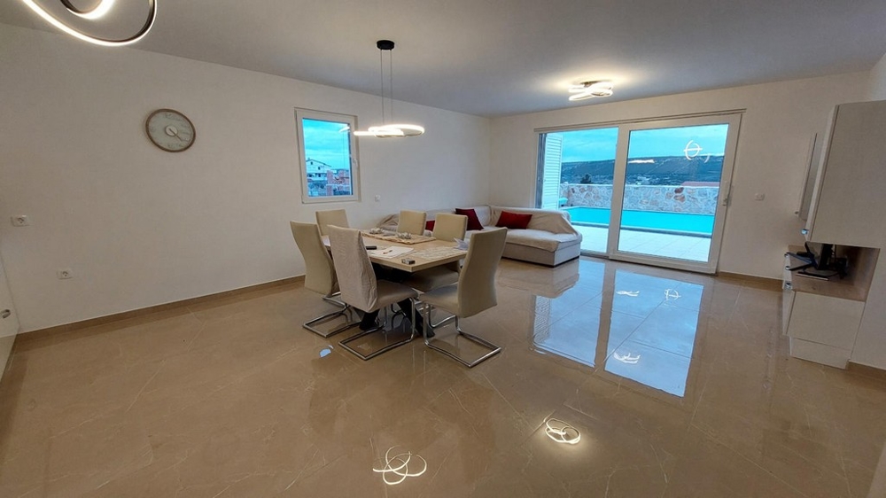 Séjour ouvert avec table à manger et vue sur la piscine, bien H3491