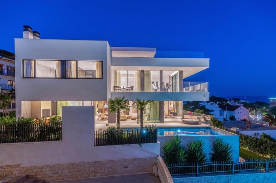 Villa illuminée avec palmiers et piscine à l'heure bleue
