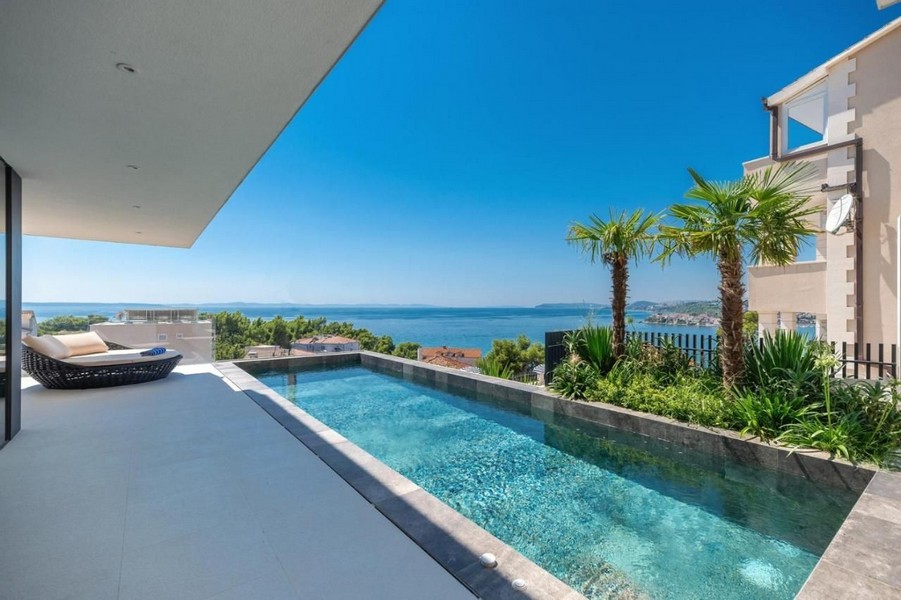 Terrasse couverte et piscine avec belle vue mer.