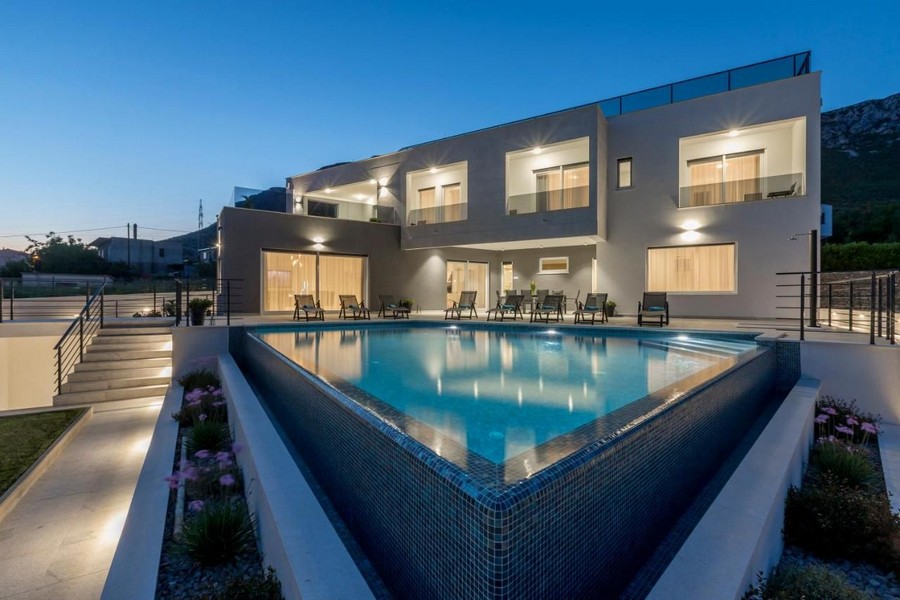Grande piscine devant la villa éclairée le soir