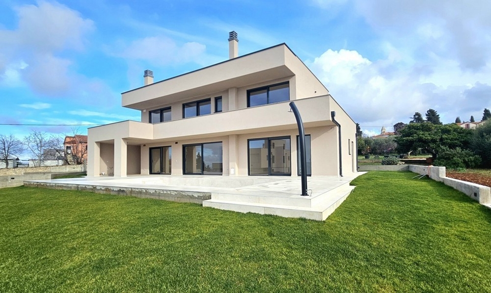 Construction neuve beige avec terrasse et pelouse fraîche