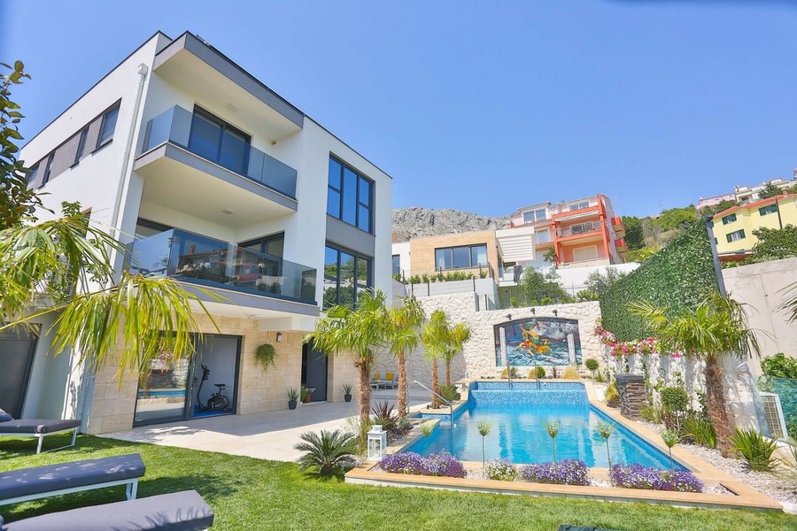 Villa avec palmiers et piscine avec mur en mosaïque dans le jardin