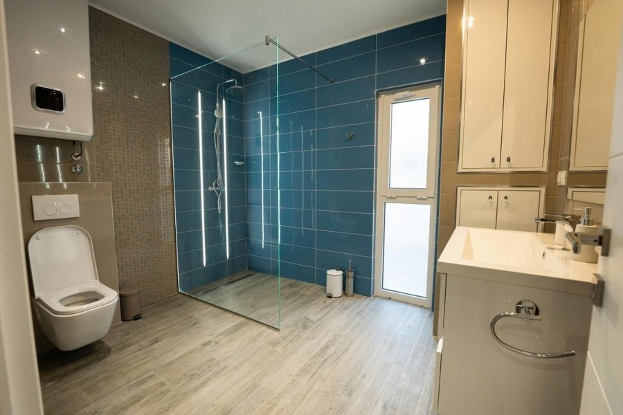 Grande salle de bains avec douche à l'italienne et carrelage bleu