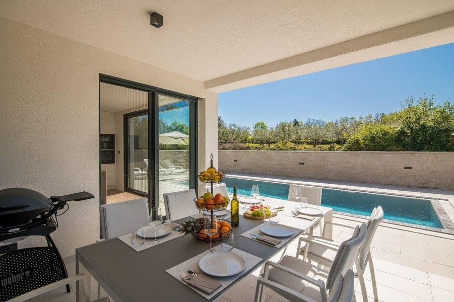 Terrasse couverte avec table à manger et vue sur la piscine